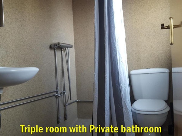 The toilet, shower, and sink in triple room's private bathroom at the Travel Inn Guesthouse.