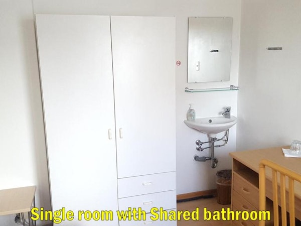 The single room with shared bathroom at Travel Inn Guesthouse has a large wardrobe and an in-room sink.
