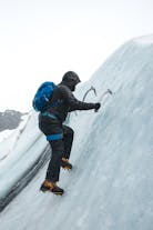 An adventurer climbing an ice wall on the Solheimajokull glacier.