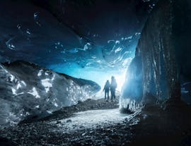Twee mensen staan in de opening van een ijsgrot in Nationaal Park Vatnajokull.