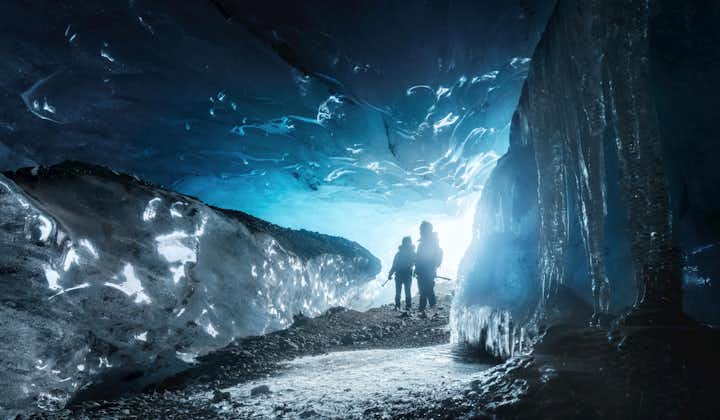 Two people standing in the opening of an ice cave in Vatnajokull National Park.