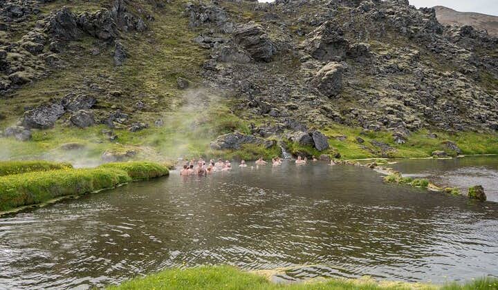 People bathe in the warm geothermal waters of a natural hot pool at Landmannalaugar in the Icelandic Highlands.