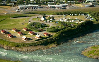 An aerial view of Gladheimar cottages with the river in front of them.