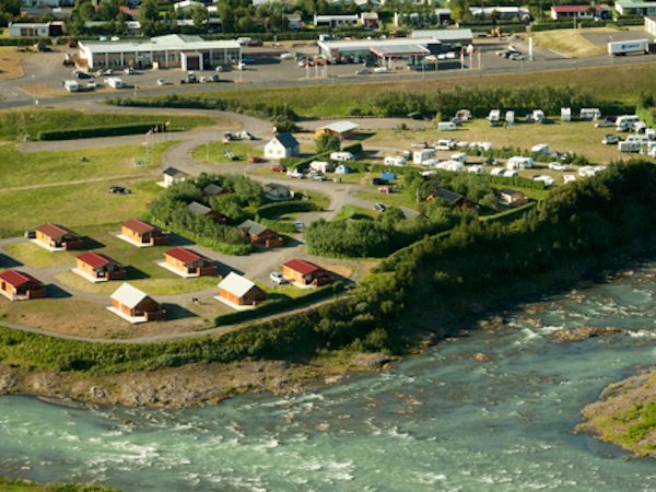 An aerial view of Gladheimar cottages with the river in front of them.