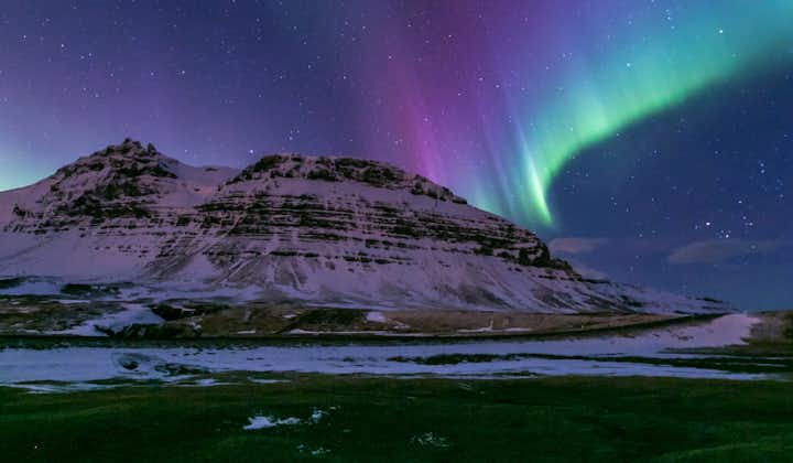 Pink, purple, blue, green, and yellow lights shine in the sky as the aurora borealis puts on a display.