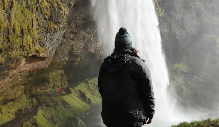 A woman looks at the Seljalandsfoss waterfall in Iceland.