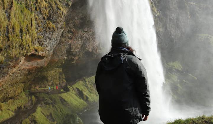 A woman looks at the Seljalandsfoss waterfall in Iceland.