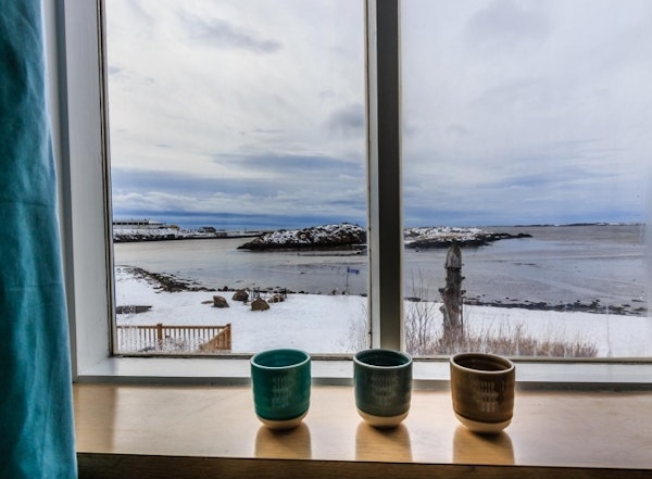 Cups on the windowsill and beautiful views across the water from Englendingavik homestay in Borgarnes.