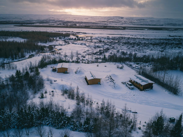 A birdseye view of the cottages at Kalda Lyngholt surrounded by a snow-covered natural landscape.