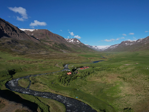 The countryside surrounding Dalasetur is stunning, with a river, mountains, and green pastures.