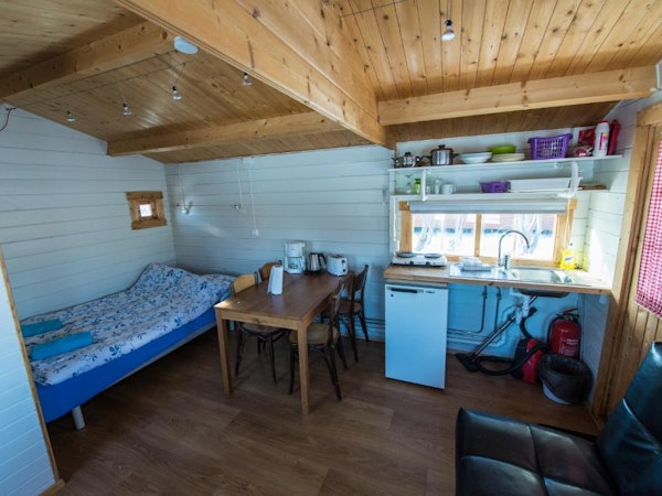 One of the Gladheimar cottages with bed, dining table and chairs, and kitchen facilities.