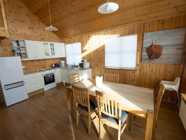 A dining table, four chairs, and a self-catering kitchen in one of the Gladheimar cottages.