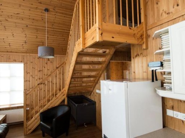 A wooden staircase at Gladheimar cottages with a tub chair underneath it.