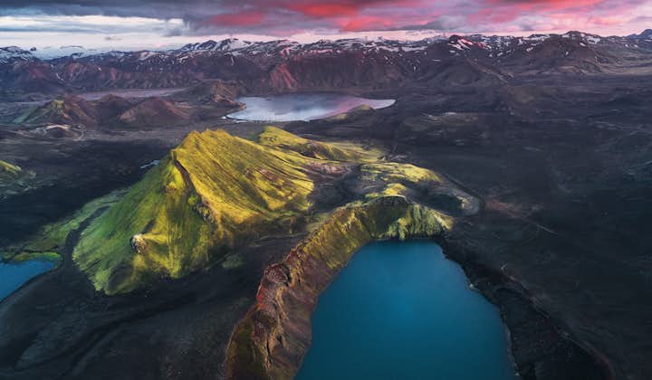 The stunning Blahylur crater lake with bright blue water amid the jagged mountain ranges in the Icelandic Highlands.