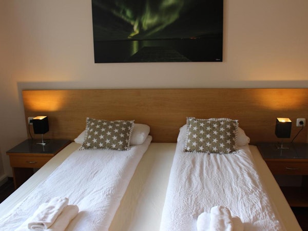 A close-up view of a bed at North Star Guesthouse Snaefellsnes with an aurora borealis picture on the wall.
