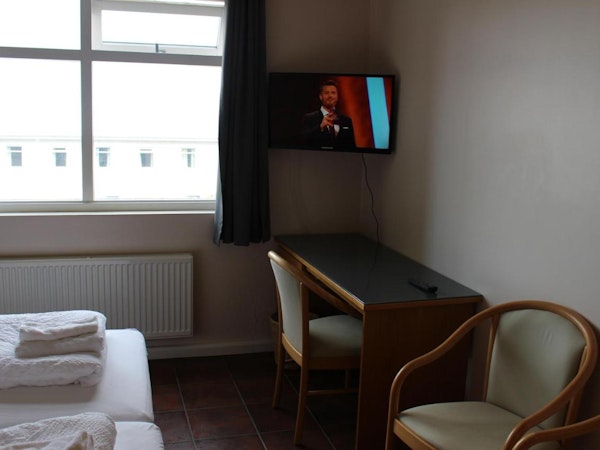 A desk, chairs, and a flatscreen television in a room at North Star Guesthouse Snaefellsnes.