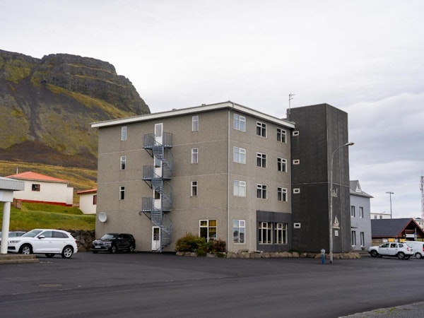 The exterior view of North Star Guesthouse Snaefellsnes with the street in front and a hill behind.