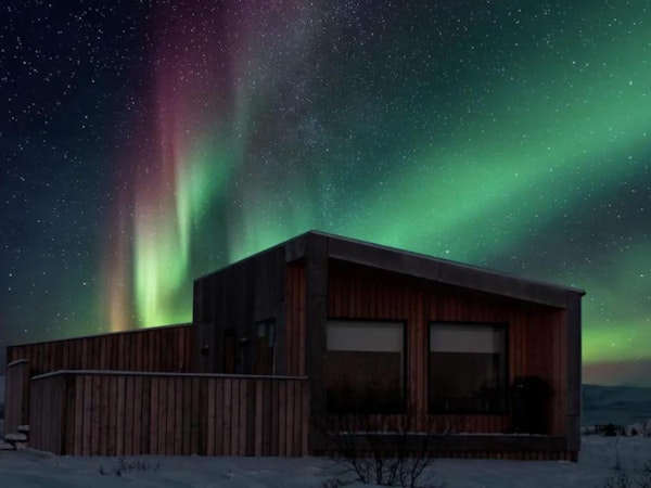 The northern lights in the sky above one of the Sula Guesthouse cottages.