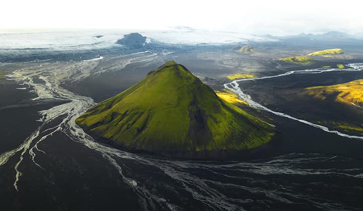 마일리펠 화산은 원뿔 모양이 인상적인데, 초록색 경사면이 아래의 검은 모래 사막과 놀랍도록 대조를 이룹니다.
