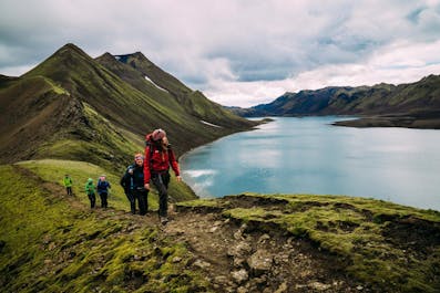 A group of hikers walk past a glittering lake in the Icelandic Highlands.