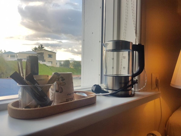 An electric kettle and tea and coffee supplies on a windowsill at Guesthouse Mikael.
