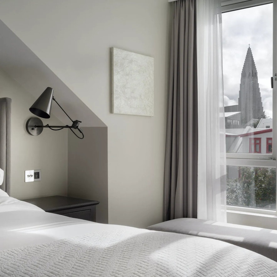 An interior view of one of the rooms at Sand Hotel in Reykjavik, with a view of the Hallgrimskirkja church through the window.