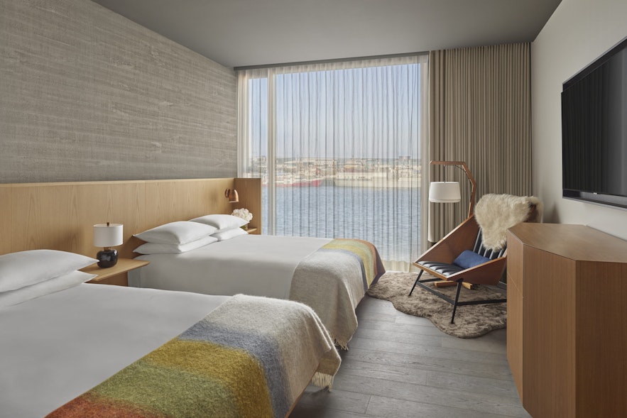 A room at EDITION Reykjavik, featuring floor-to-ceiling windows and two large double beds.