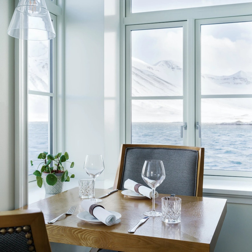 A dining table in front of a large window with a sea view.
