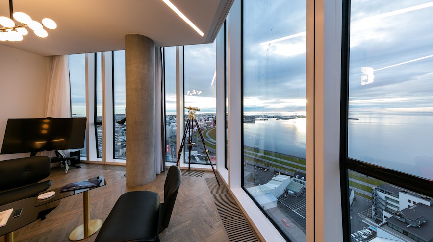 The interior of one of the rooms at Tower Suites Reykjavik, featuring an incredible city and harbor view through large windows.