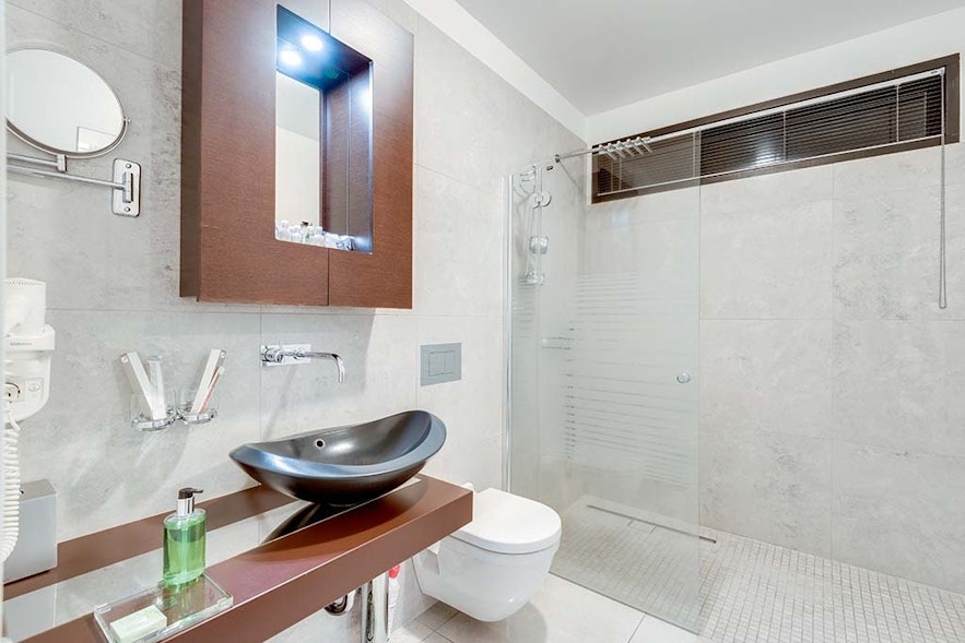 雷克雅未克黑珍珠酒店标准套房的浴室，配有大型步入式淋浴间、马桶、面盆和镜子