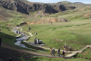 A group of people hiking on a tour near the Reykjadalsa river in the Reykjadalur valley in Iceland.