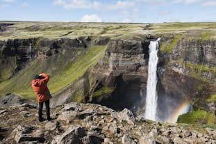 A man takes a picture of Haifoss waterfall, one of Iceland's highest waterfalls.