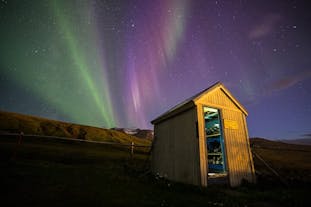 A beautiful view of the northern lights behind a small wooden structure.