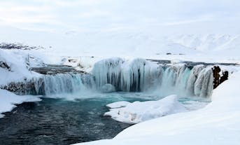 Winter wonderland at Godafoss, also known as 'water of the gods,' a breathtaking waterfall in Iceland with frozen landscapes and turquoise waters.
