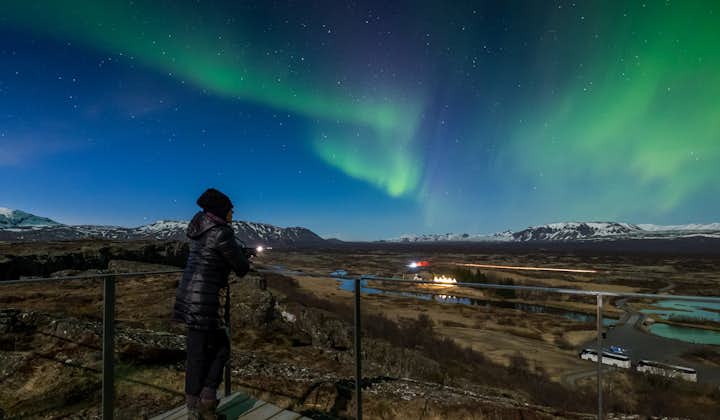 Wrapped in warm layers, stand mesmerized as the green and pink lights create a celestial spectacle above the Icelandic wilderness.