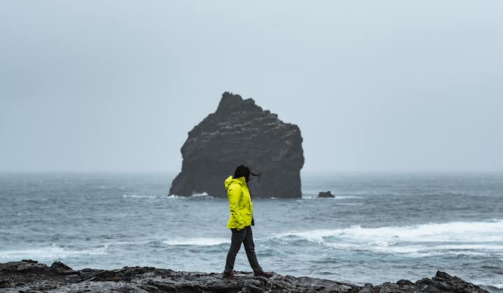 A person walking on the volcanic coastline of the Reykjanes Peninsula.