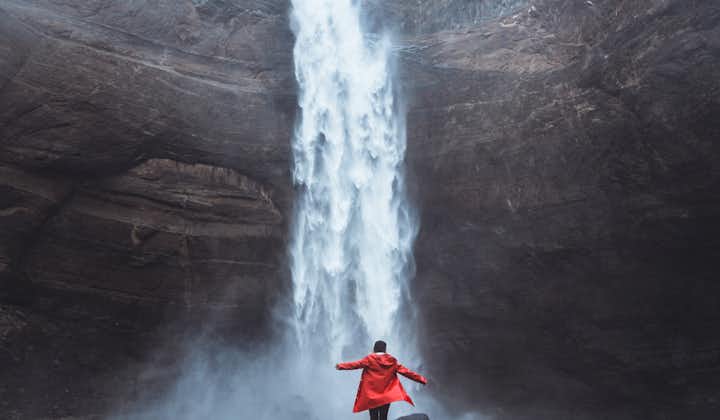 A person stands at the bottom of Haifoss waterfall, one of the tallest waterfalls in Iceland.