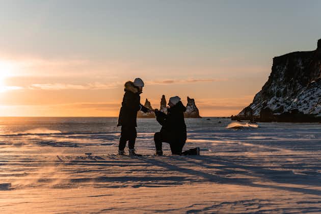 A man proposes to a woman at sunset on a black-sand beach on Iceland's South Coast.