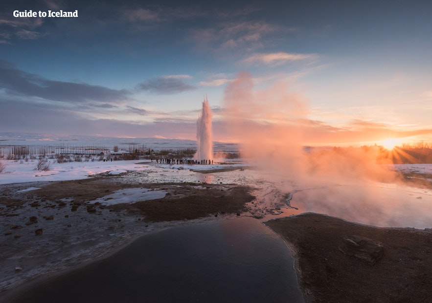 Boiling water erupts among snowy landscapes at Geysir.