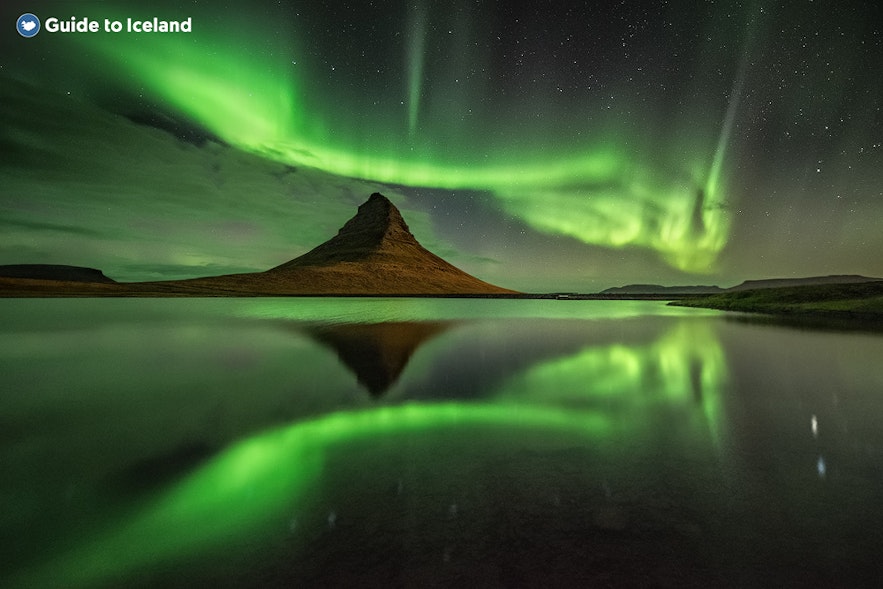 La aurora boreal, reflejada perfectamente en las aguas, sobre la montaña Kirkjufell.