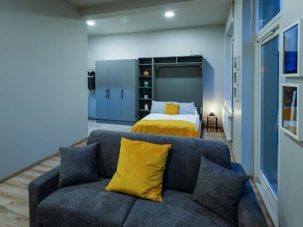 A comfortable sofa and a bed behind it in a living area at Center Apartments.