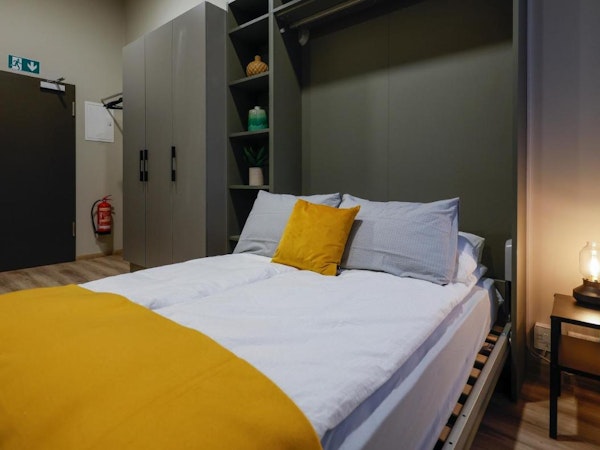 A comfortable bed with shelving and a closet behind it at Center Apartments in Reykjavik.