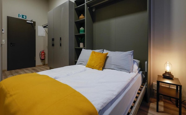 A comfortable bed with shelving and a closet behind it at Center Apartments in Reykjavik.