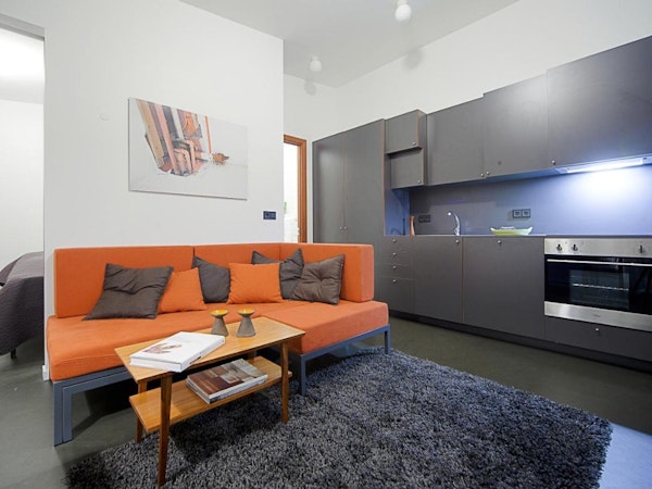 An open-plan living space at Astro Apartments with a sofa and kitchenette.