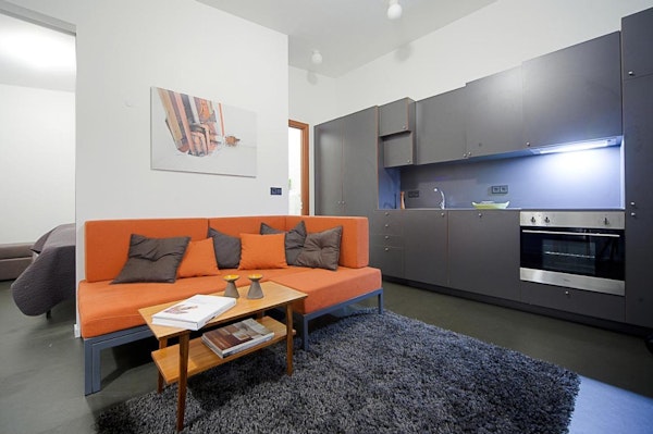 An open-plan living space at Astro Apartments with a sofa and kitchenette.