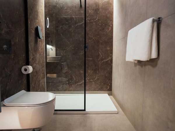 A modern bathroom with a toilet, shower, and towels at Konvin Hotel by Keflavik Airport.
