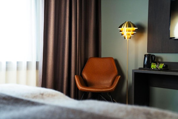 A desk, lamp, and bed in a room at Konvin Hotel near Keflavik Airport.