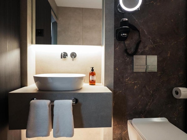 A modern bathroom with a toilet, basin, and hand towels at Konvin Hotel by Keflavik Airport.