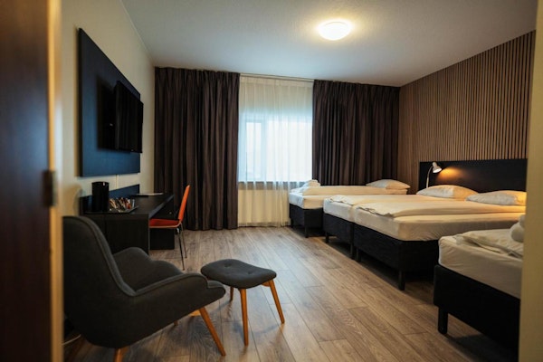 A quadruple room with a desk and chair, television, and seating area at Konvin Hotel near Keflavik airport.