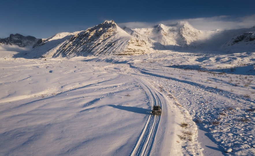 Rental jeep driving on a snowy road in the mountains of Iceland during winter